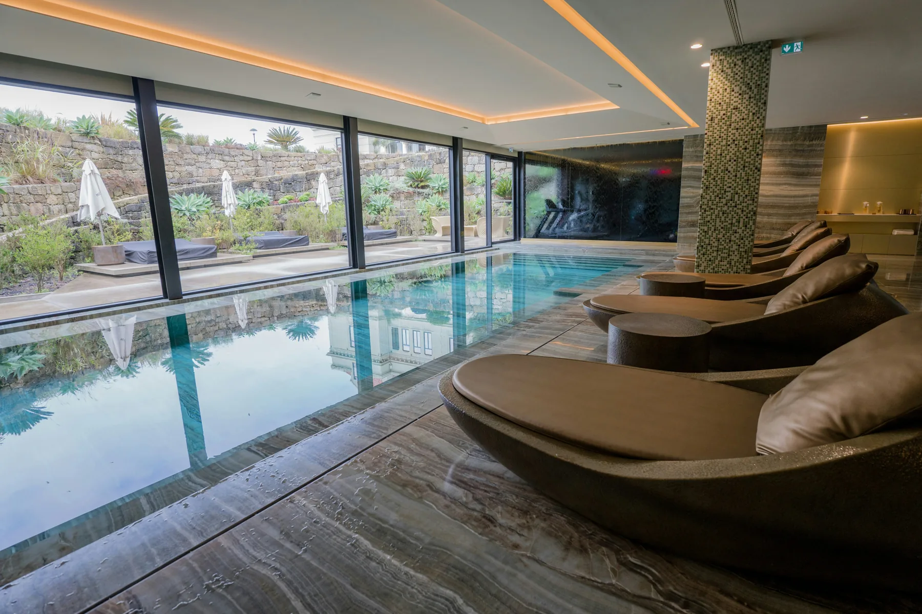 Illustrative indoor pool with lounge chairs and large windows