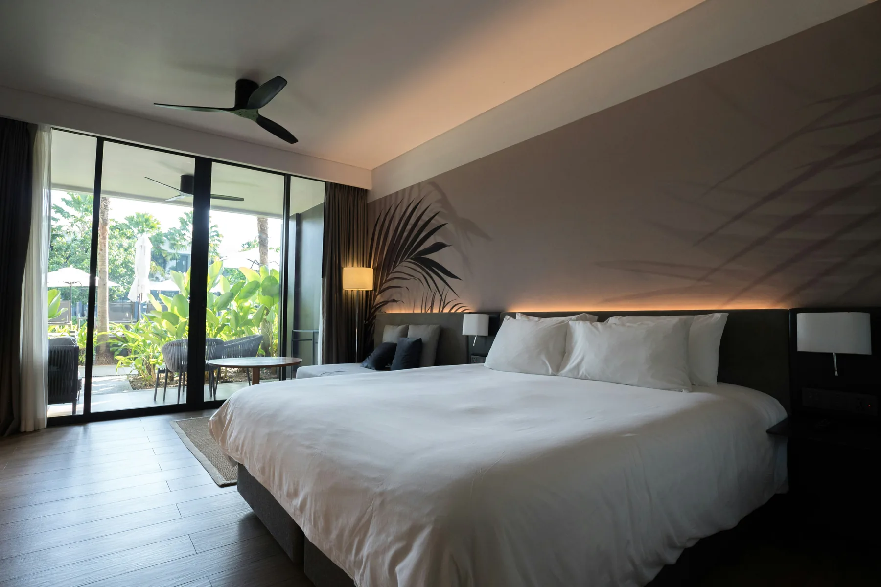 Illustrative modern hotel room with a large bed and garden-facing windows